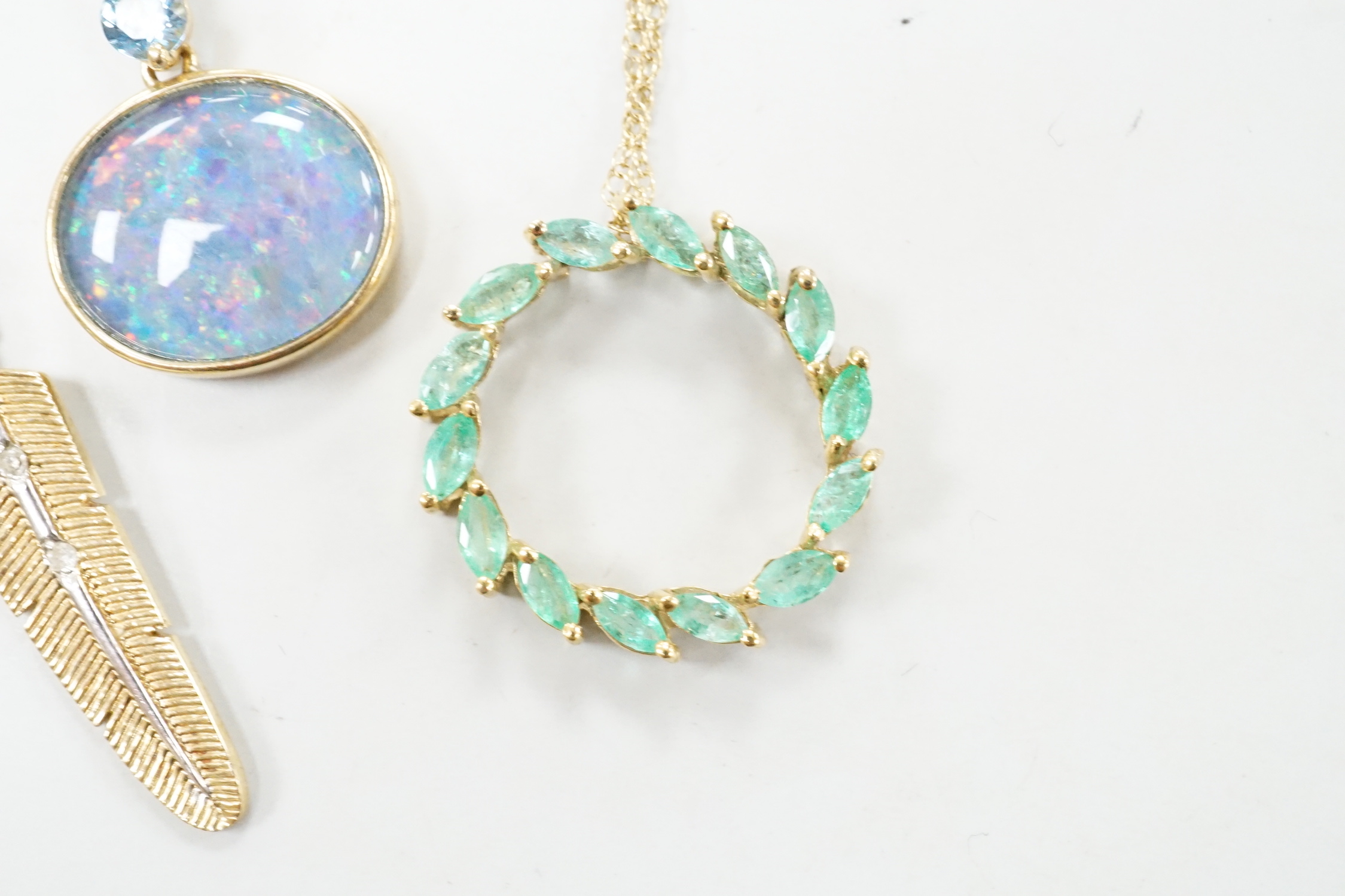 Three assorted modern 9ct or yellow metal and gem set pendants, on 9ct chains including opal doublet and blue topaz, feather shape and emerald set circular and a similar 10k pendant, on a 10k chain, longest 52cm, gross w